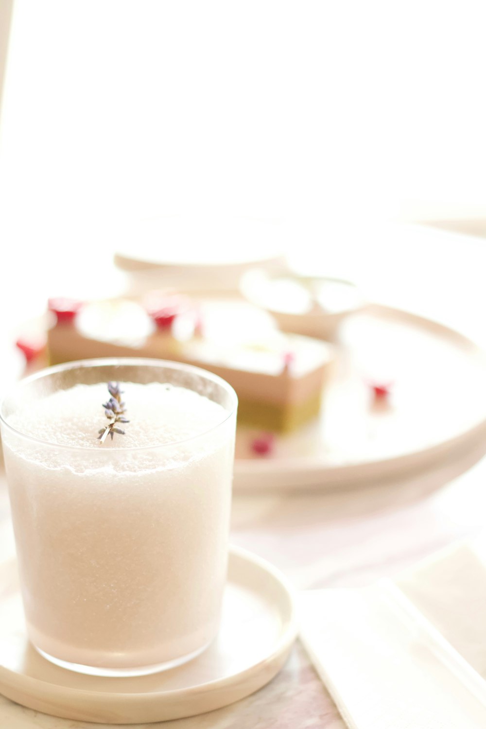 clear drinking glass with white liquid on white ceramic saucer