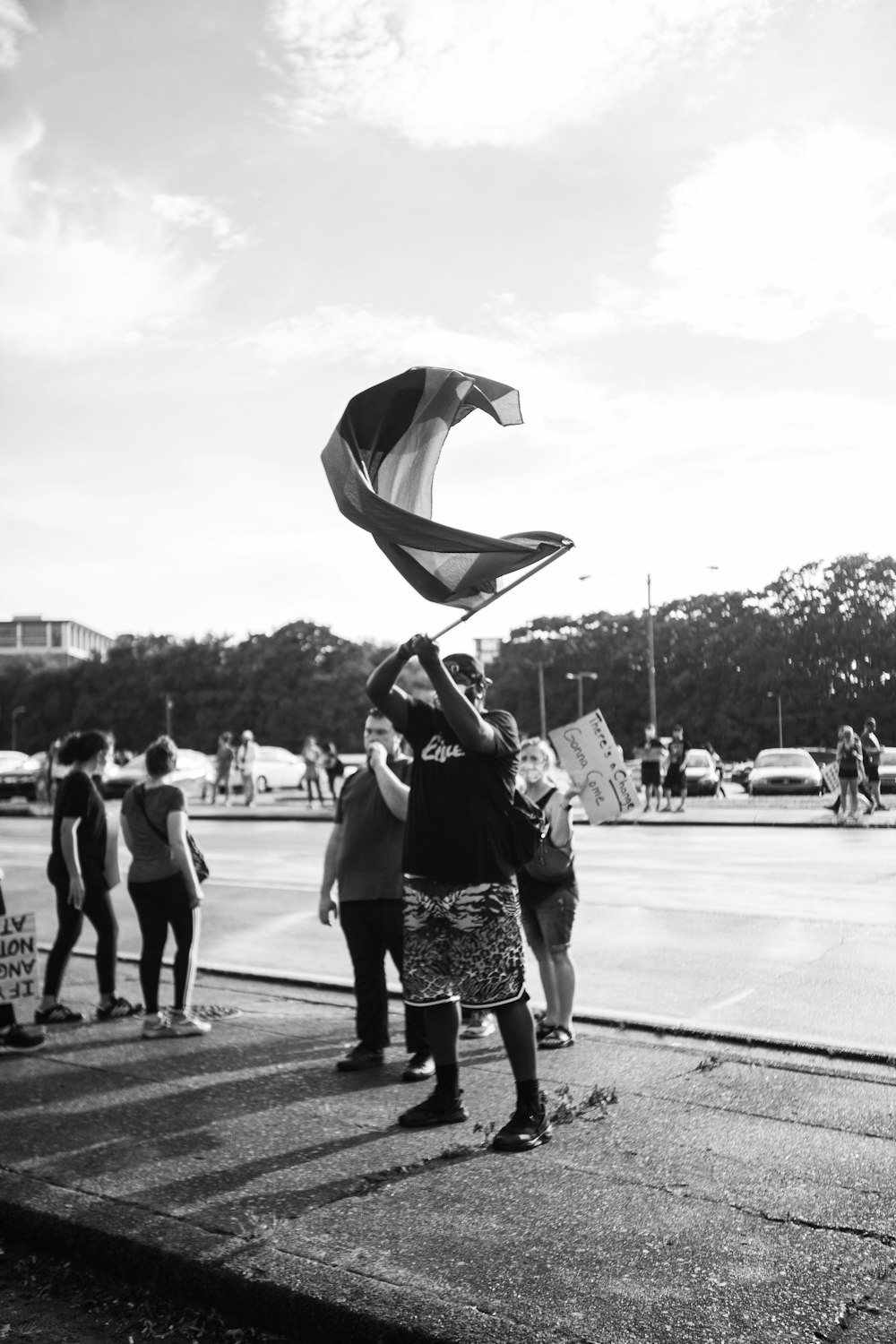 grayscale photo of woman in black dress dancing on street