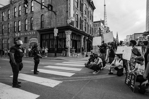 grayscale photo of people walking on street near building