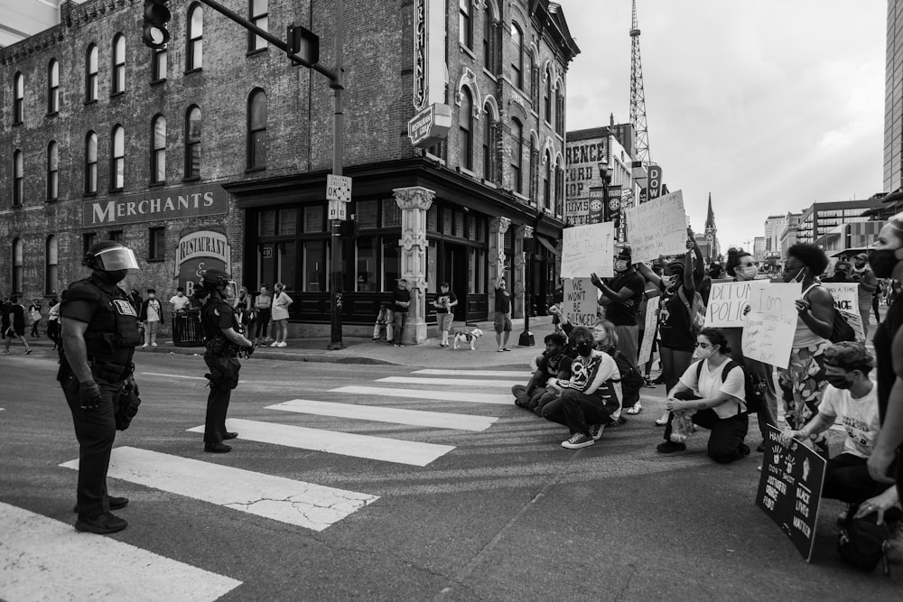 grayscale photo of people walking on street near building