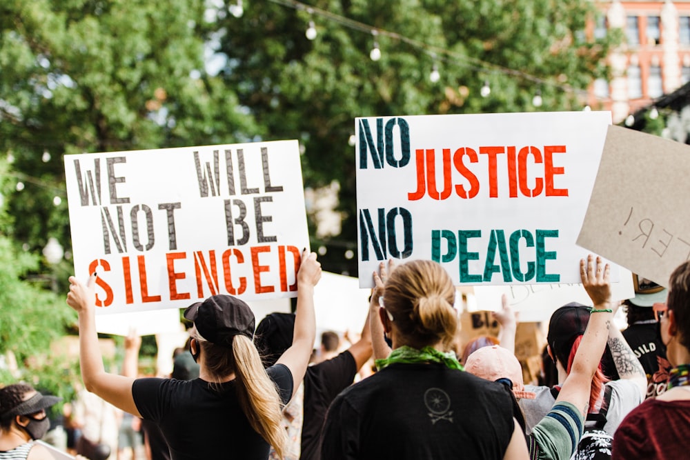 woman in black shirt holding white and green signage