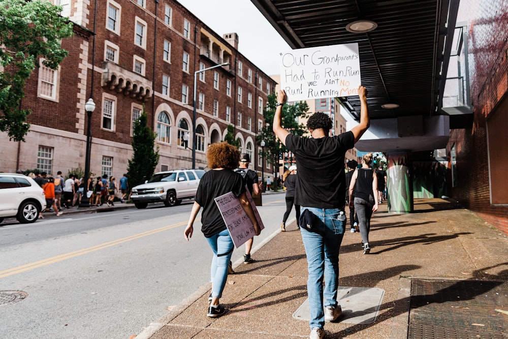 man in black t-shirt and blue denim jeans holding white printer paper during daytime