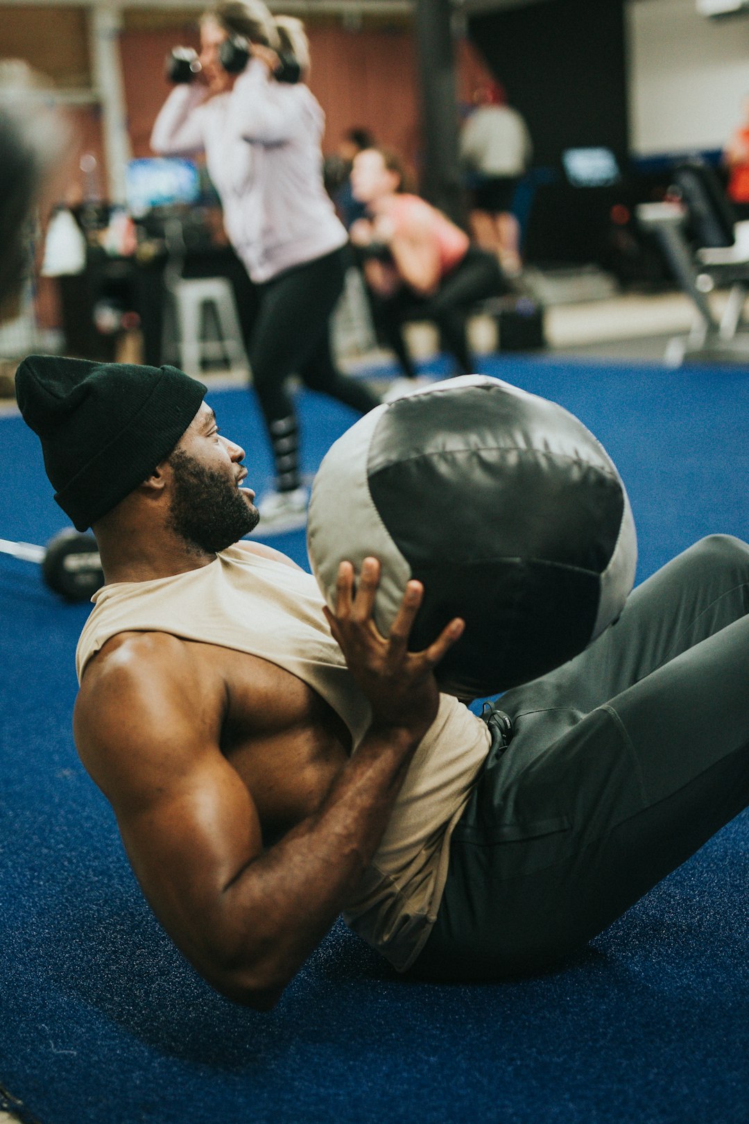 topless man in black pants sitting on blue exercise ball
