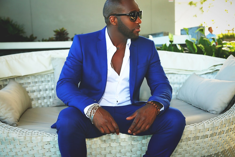 man in blue suit sitting on white couch