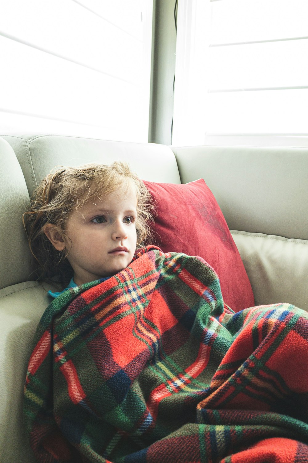 girl covered with red and black plaid blanket