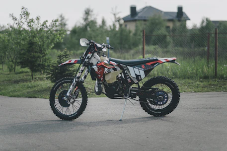 A vibrant motocross bike ready for off-road adventure in a lush green forest.
