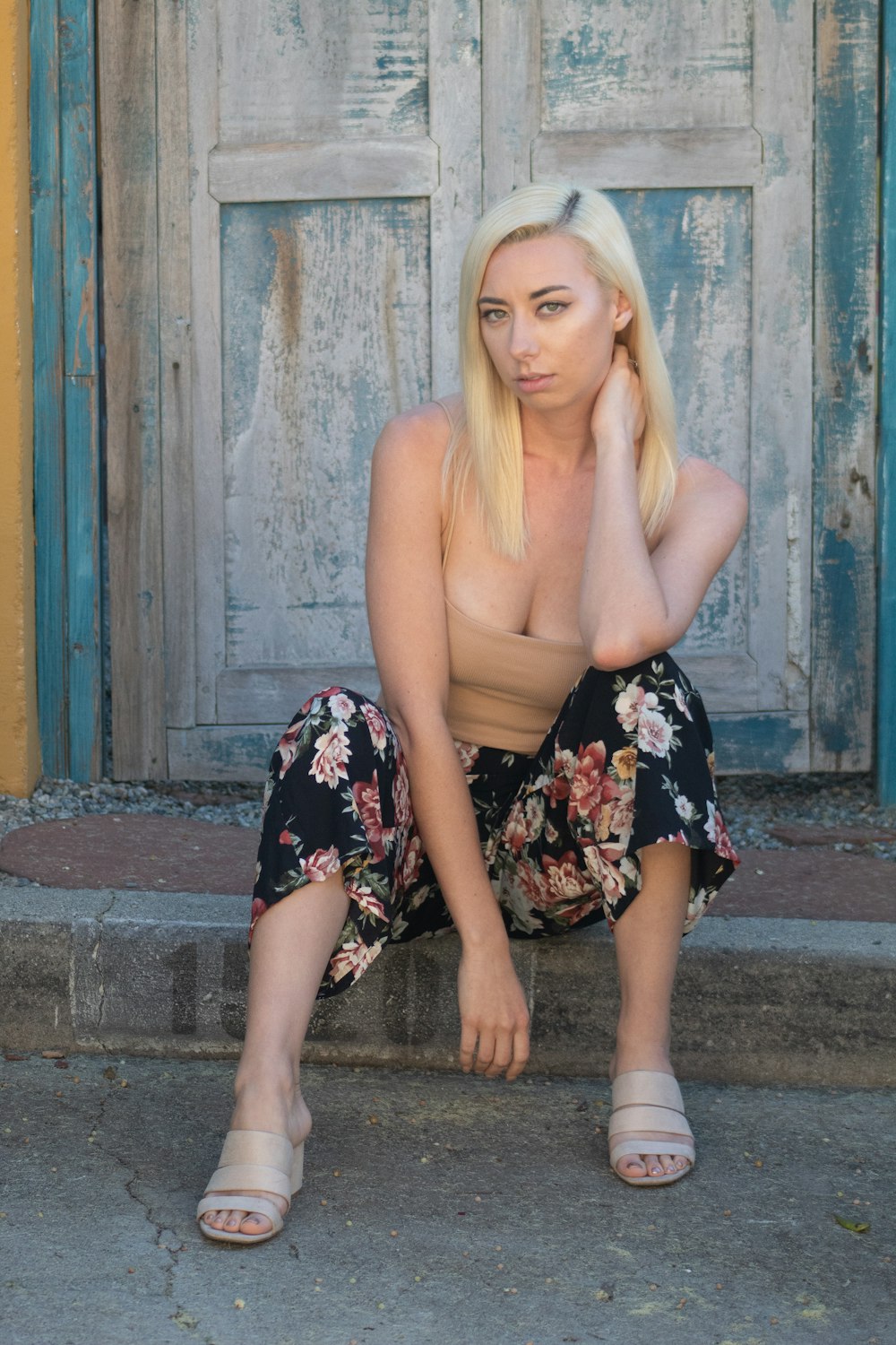 woman in black and white floral dress sitting on brown concrete floor