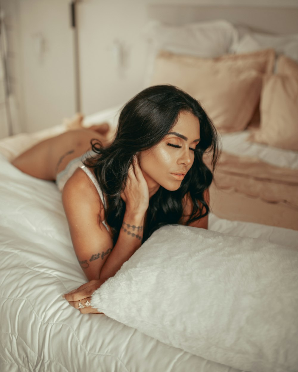 mujer con camiseta blanca sin mangas acostada en la cama
