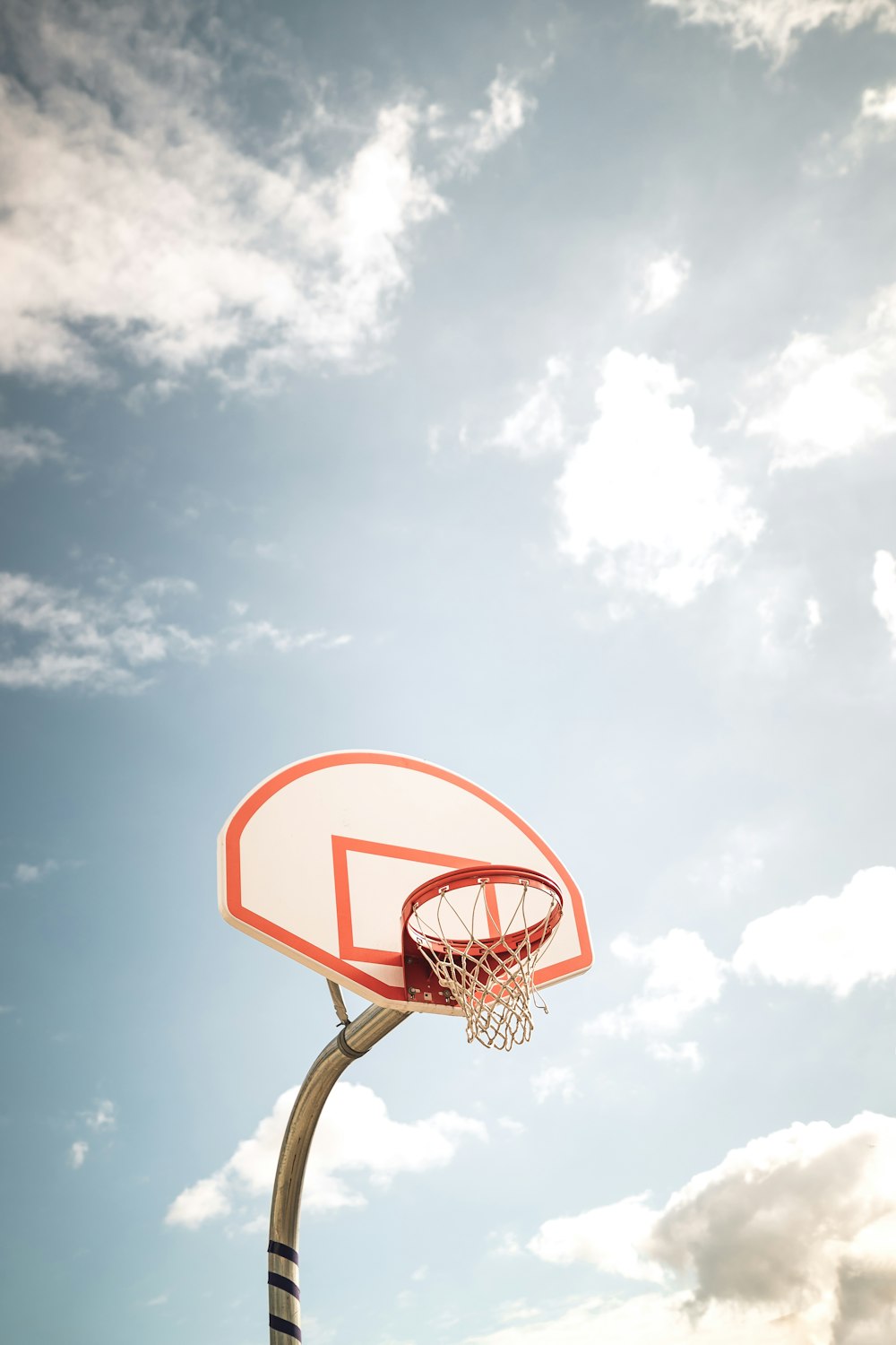 basketball hoop under blue sky and white clouds during daytime