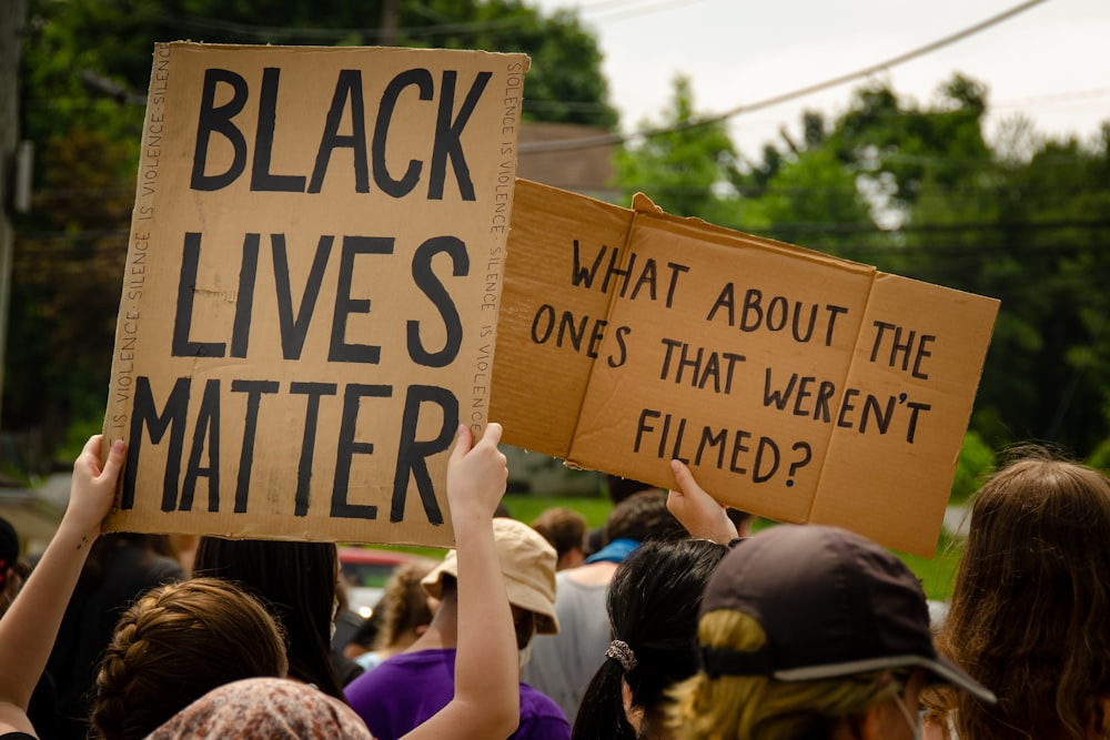 people holding brown wooden signage during daytime