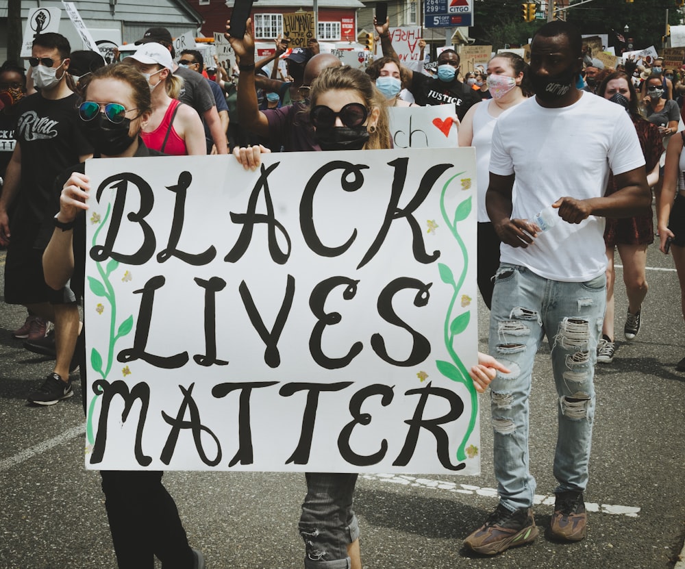 man in white crew neck t-shirt holding white and black banner