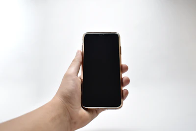 Grayscale close-up of a hand holding a smartphone with an ad display.