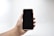 A close-up of a modern smartphone held in a person's hand against a clean background.
