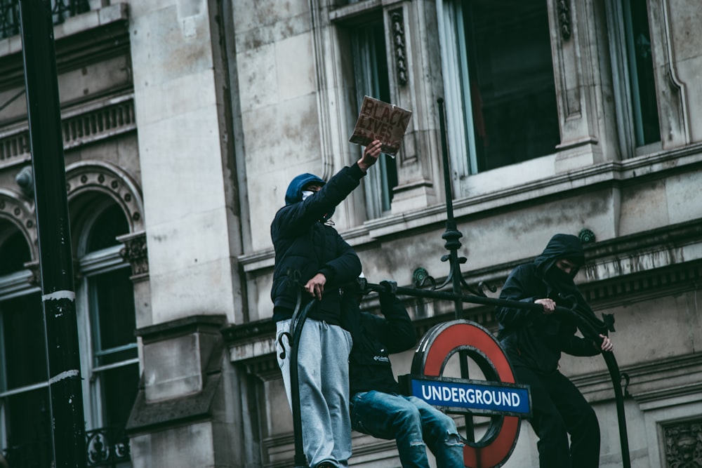 man in black leather jacket and blue denim jeans holding brown stick