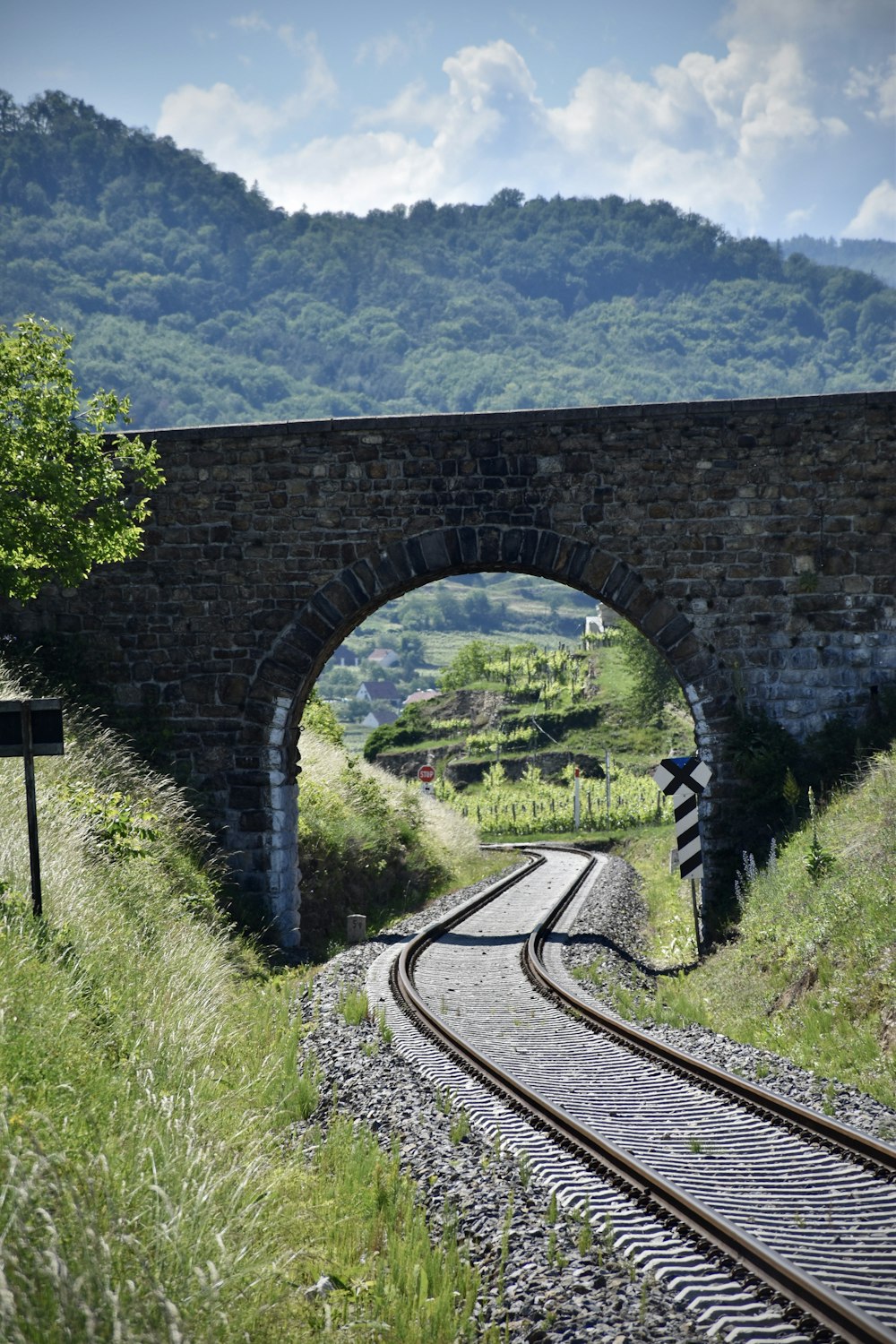 brown metal train rail near green grass field during daytime