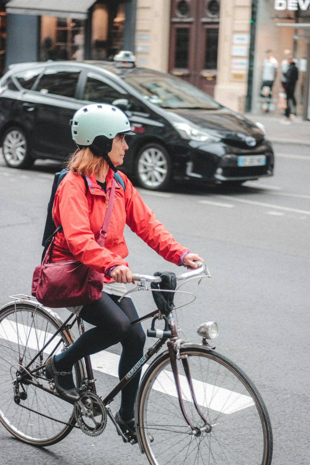 woman in red jacket riding bicycle on road during daytime