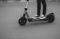 A person wearing sneakers stands on an electric scooter labeled with the text 'dott' on a smooth surface.