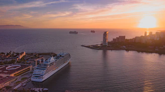 Sunset casting golden hues over a modern cruise liner docked at a vibrant port.