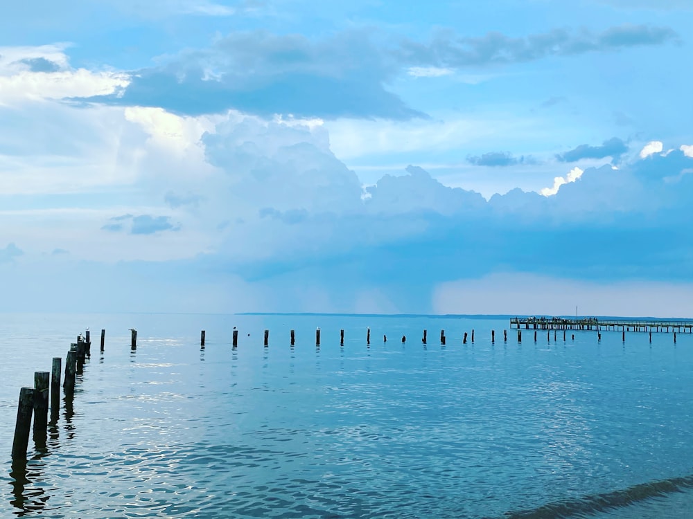 white wooden dock on sea under white clouds and blue sky during daytime