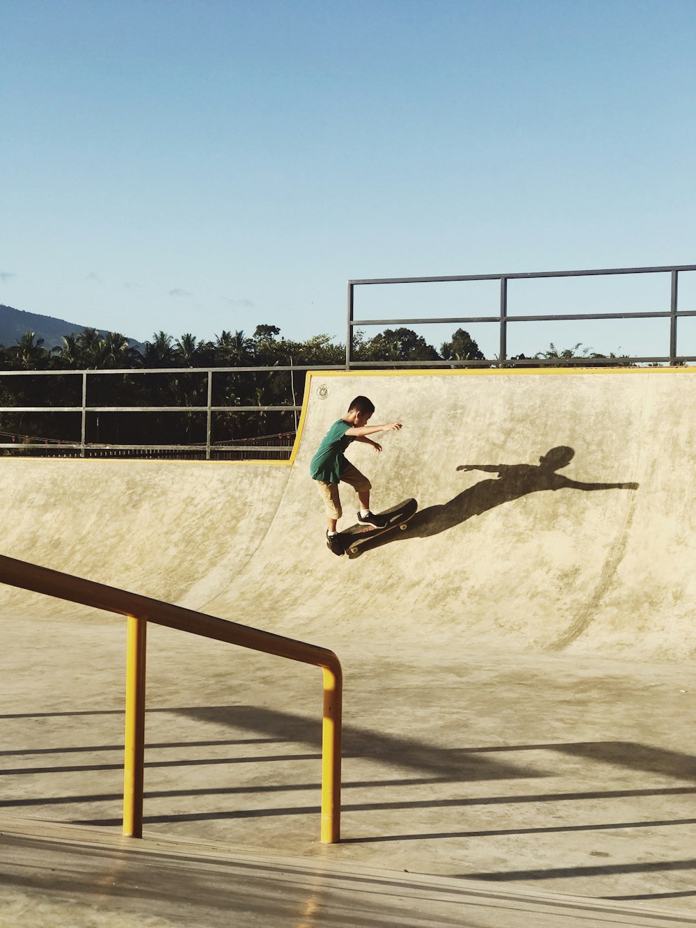 man in black t-shirt and black pants doing skateboard stunts on brown sand during daytime