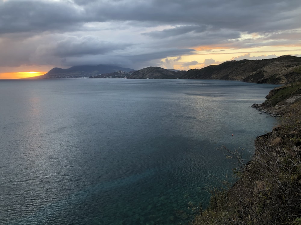 body of water near mountain during daytime