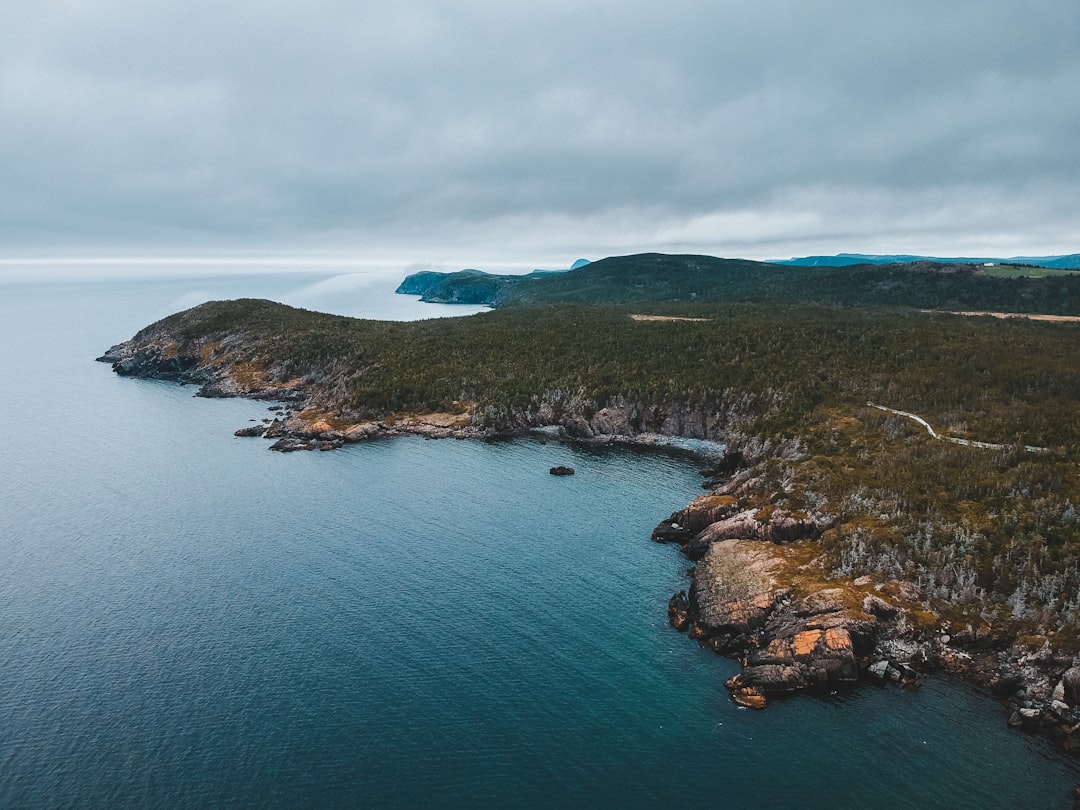 green and brown island in the middle of blue sea under white clouds during daytime