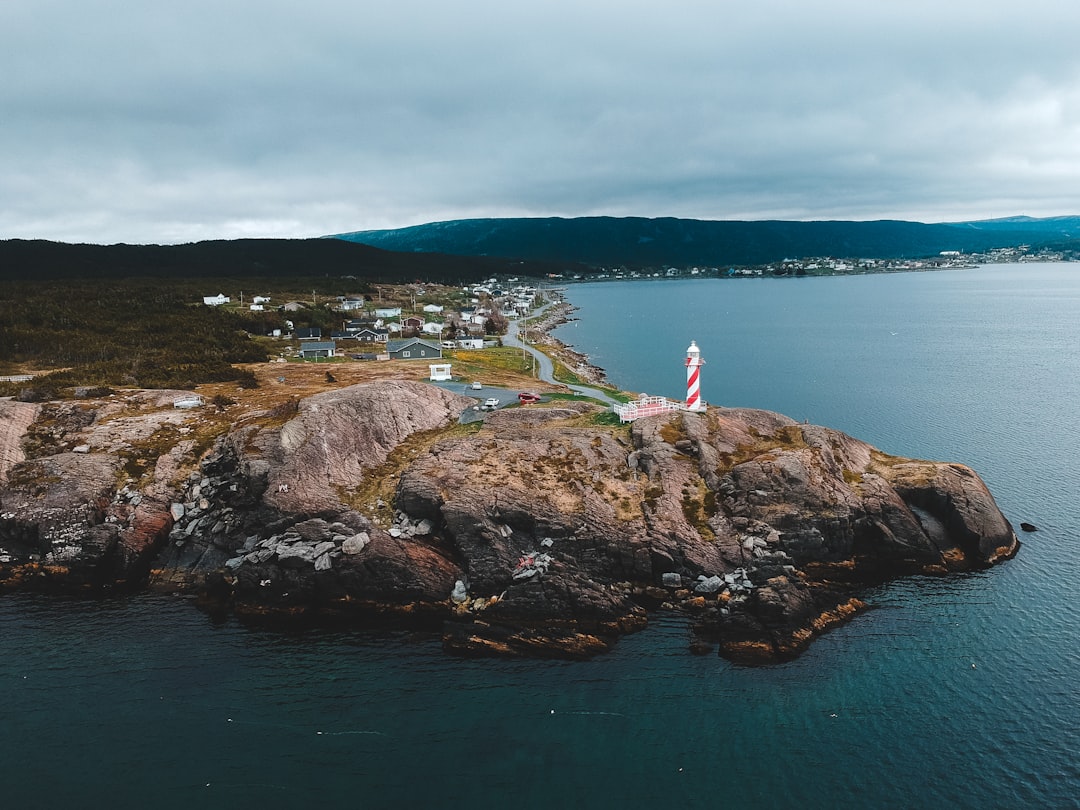 woman in white dress standing on rock formation near body of water during daytime