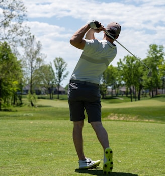 man in white t-shirt and black shorts holding golf club