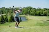 man in white t-shirt and black shorts playing golf during daytime
