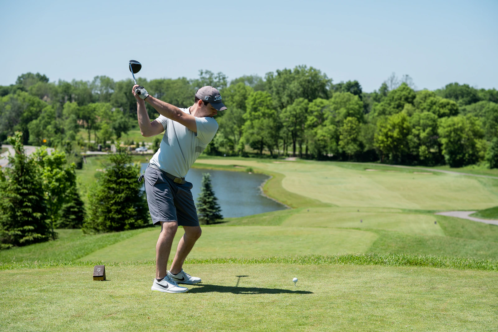 A golfer teeing off on a parkland course