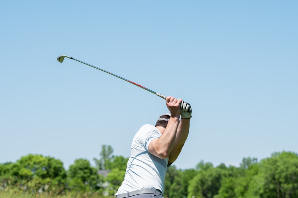 hombre con camiseta blanca sin mangas y pantalones cortos blancos jugando al golf durante el día