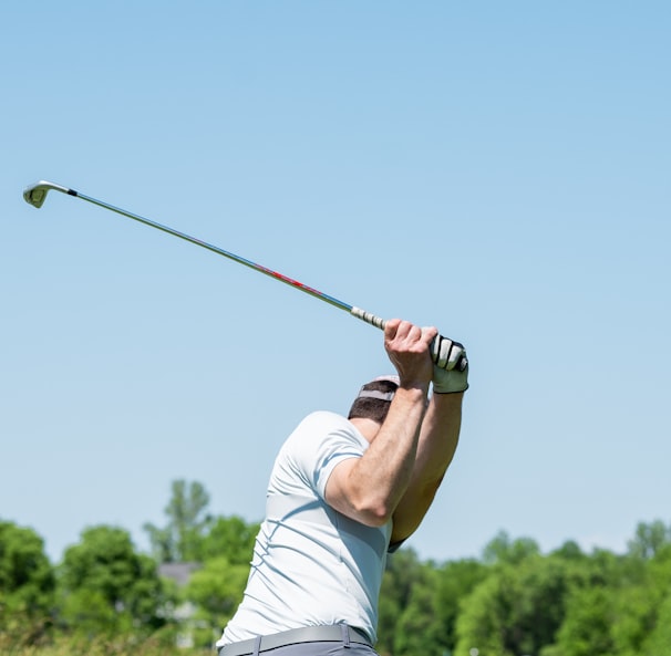 man in white tank top and white shorts playing golf during daytime