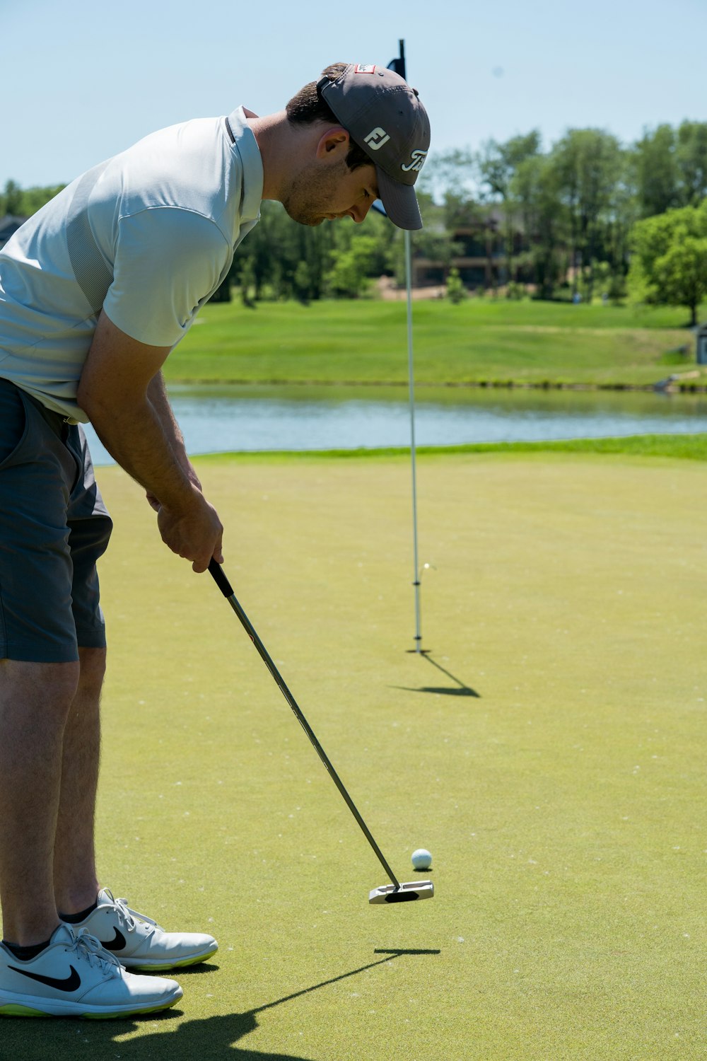 흰색 티셔츠와 갈색 반바지를 입은 남자가 낮에 골프를 친다