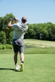 man in white t-shirt and black shorts playing golf during daytime