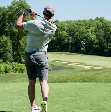 man in white t-shirt and black shorts playing golf during daytime