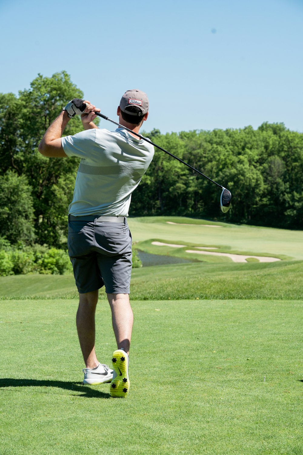 homme en t-shirt blanc et short noir jouant au golf pendant la journée