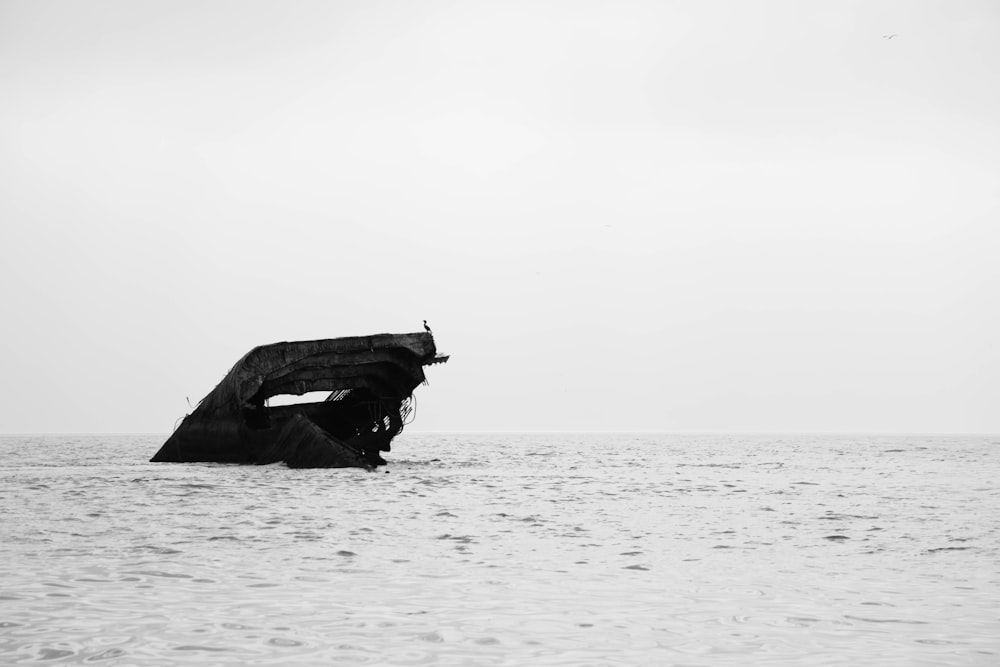 foto in scala di grigi di una barca in mezzo al mare