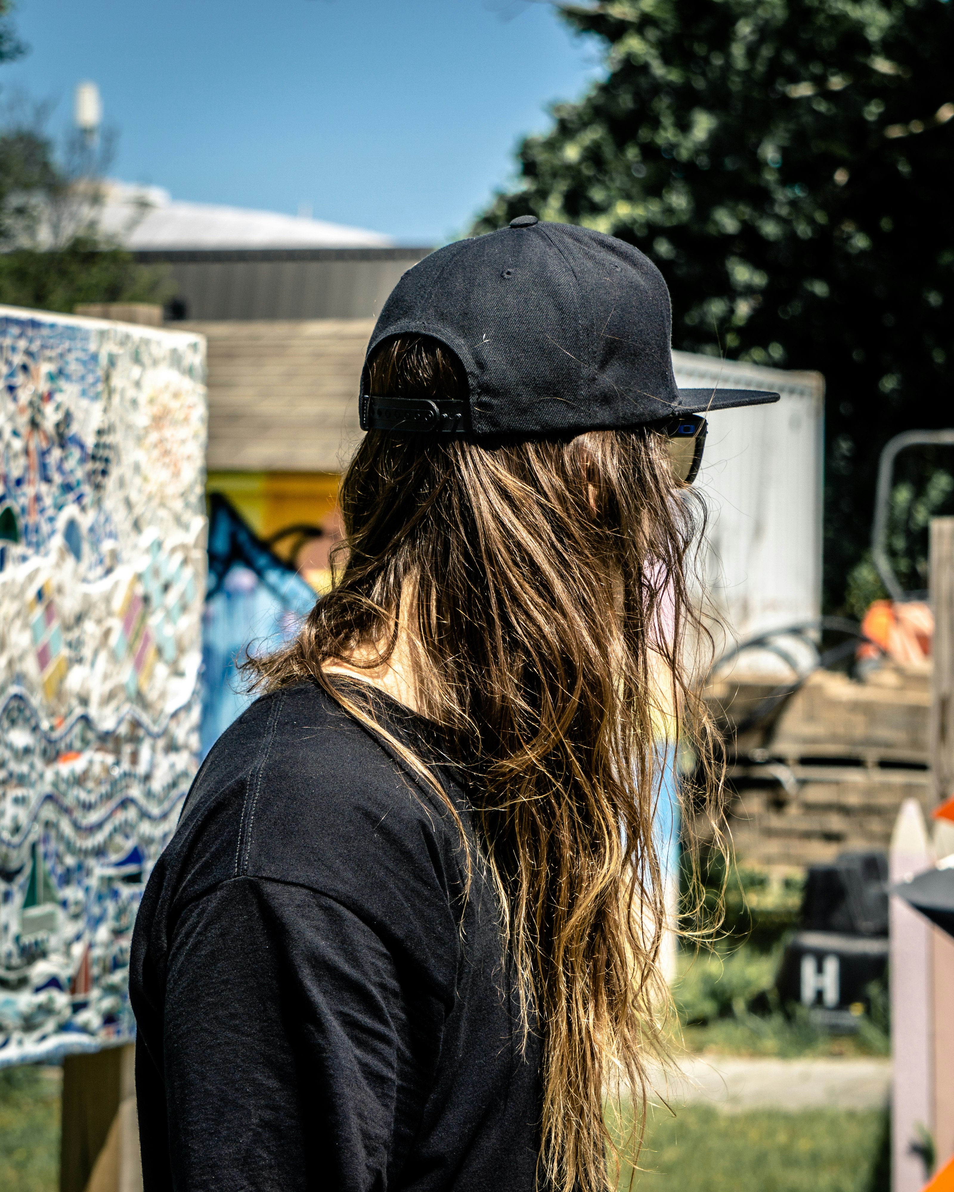 woman in black shirt and black cap standing near graffiti wall during daytime