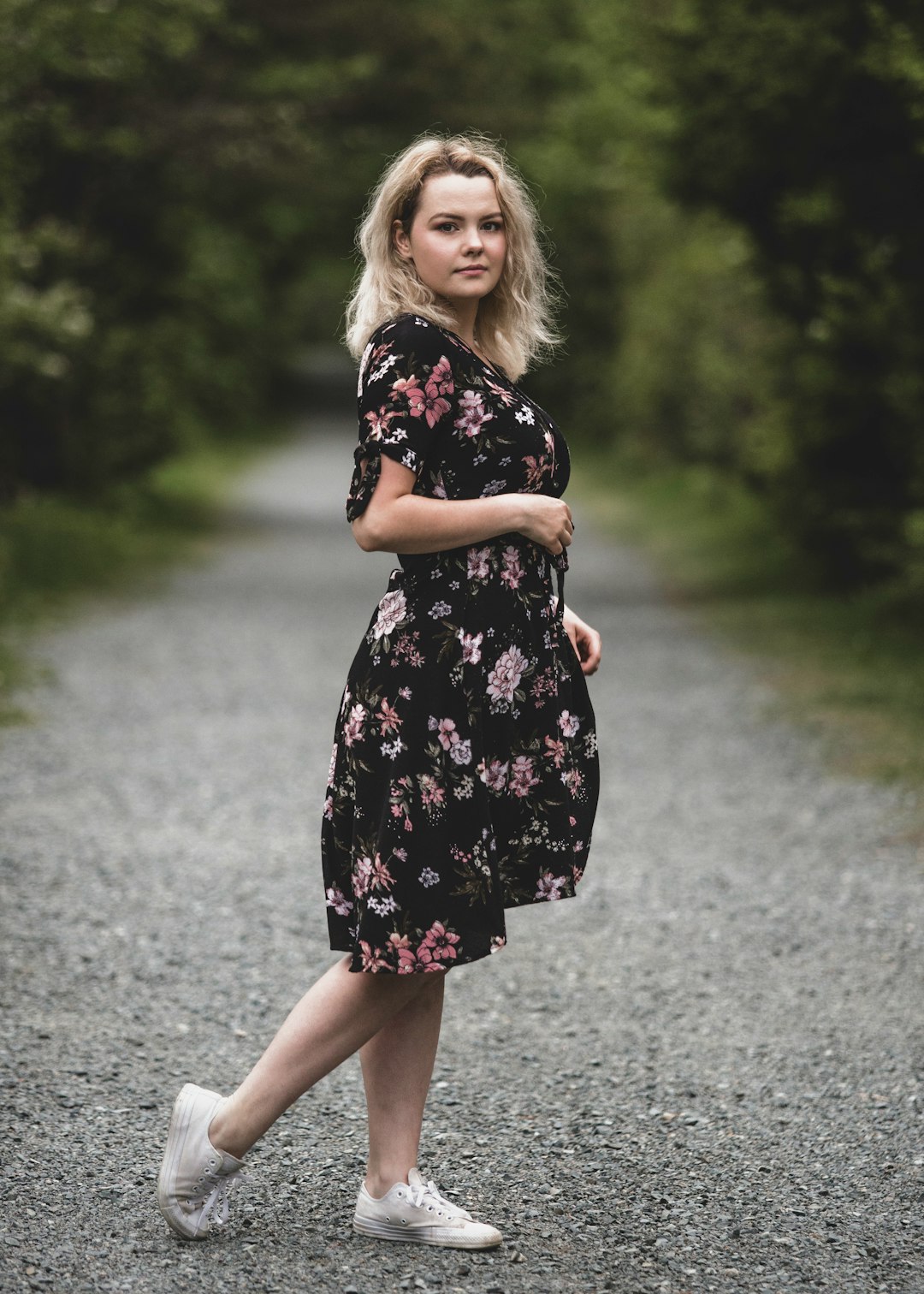 girl in black and white floral dress standing on gray asphalt road during daytime