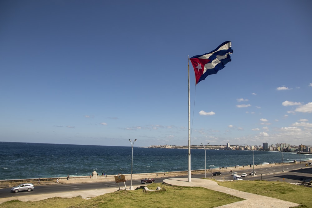 red white and blue flag on pole near sea during daytime