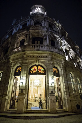 A grand hotel entrance bathed in royal blue and gold lighting, welcoming guests warmly at dusk.