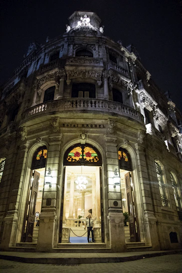 A grand hotel entrance adorned with royal blue and gold accents under soft evening lights.