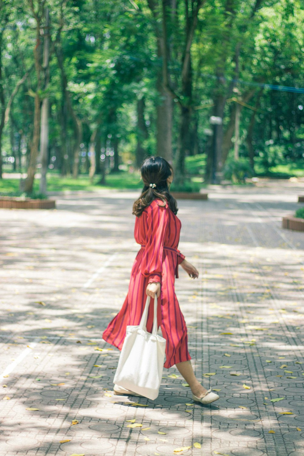 woman in red dress walking on sidewalk during daytime