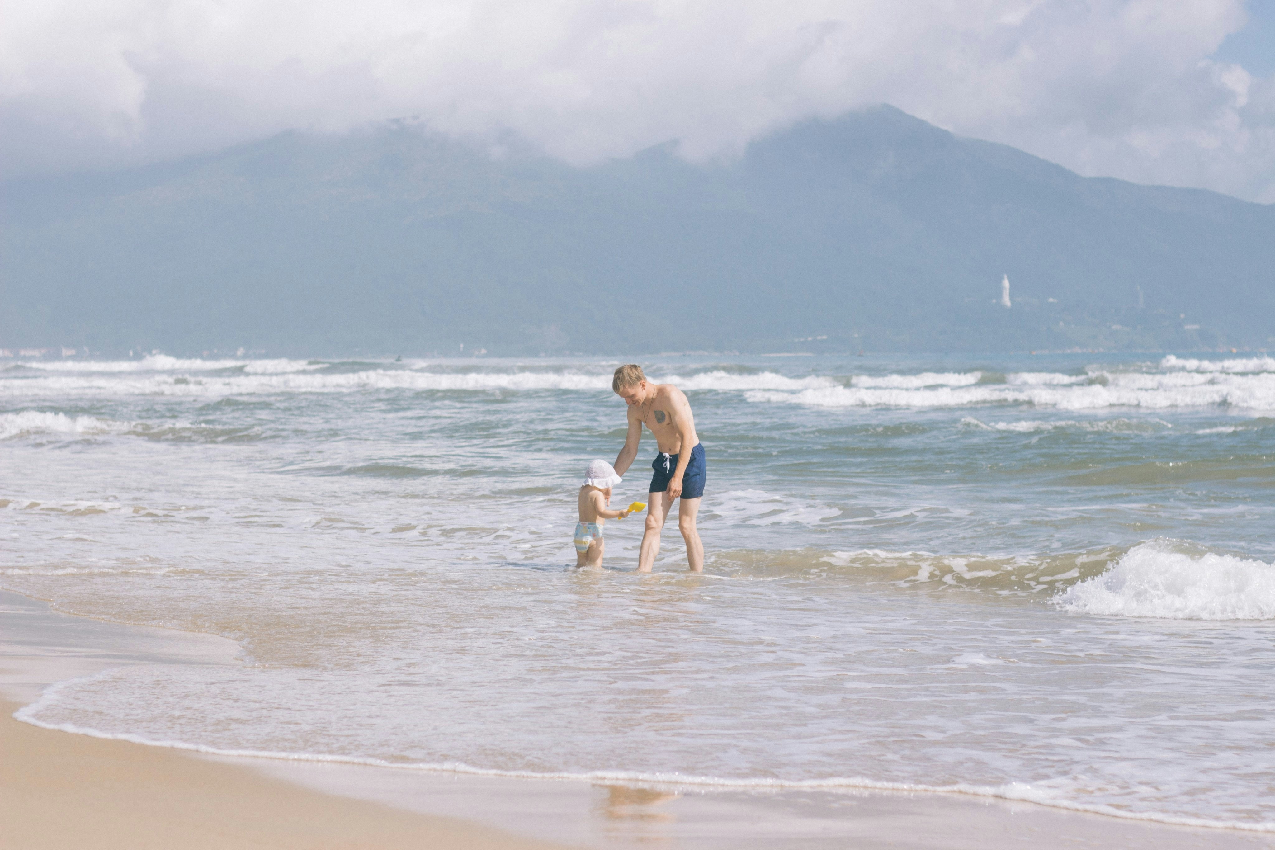 man and woman walking on beach during daytime