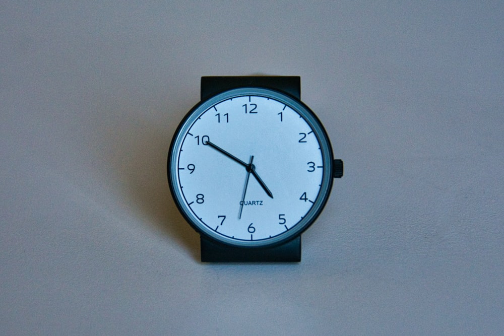 black round analog wall clock at 10 10