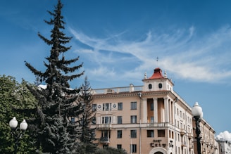 beige concrete building near green trees under blue sky during daytime