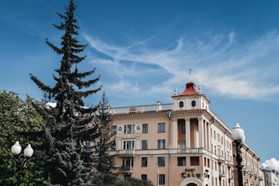 beige concrete building near green trees under blue sky during daytime