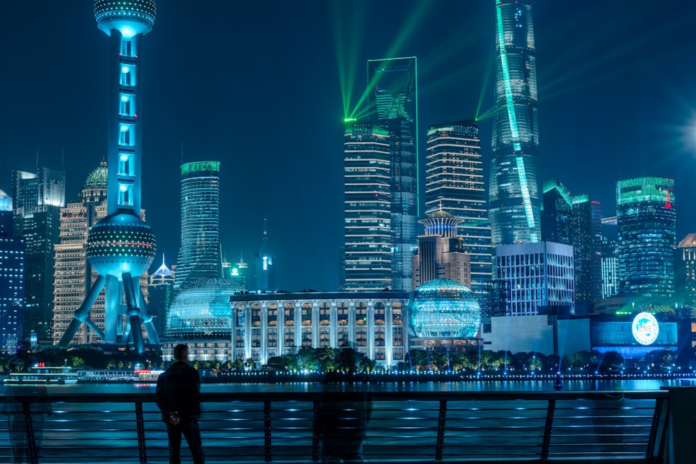 people walking on sidewalk near lighted city buildings during night time