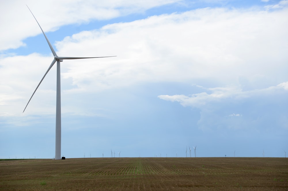 wind turbines on green grass field under white clouds during daytime