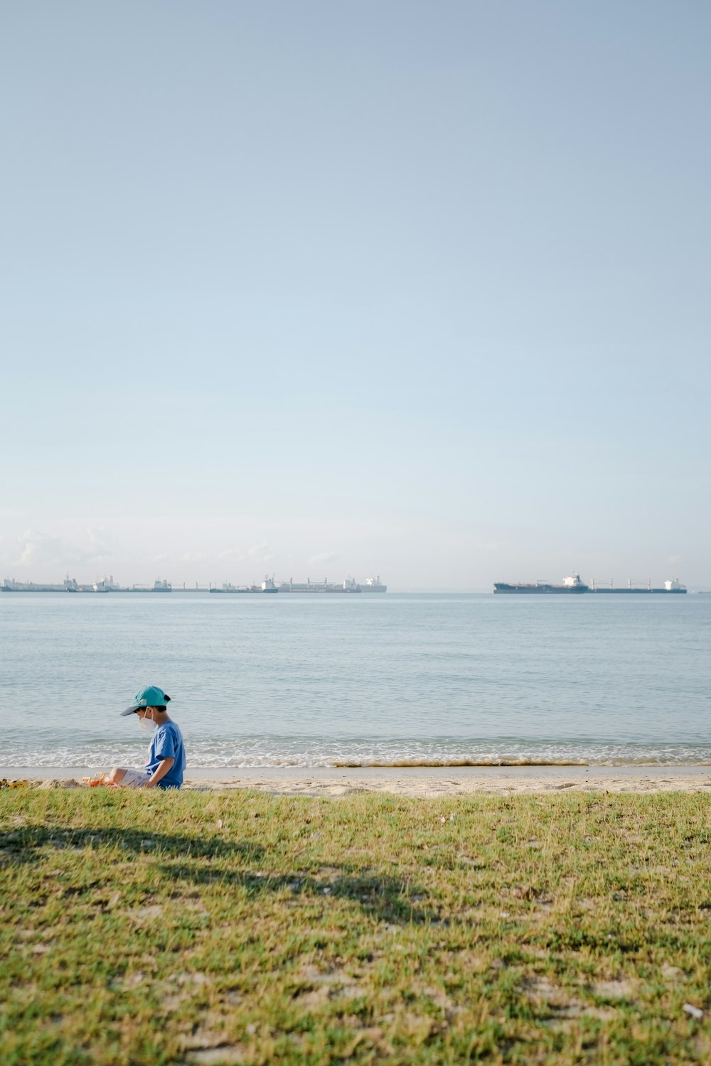 person in blue shirt standing on green grass field near body of water during daytime